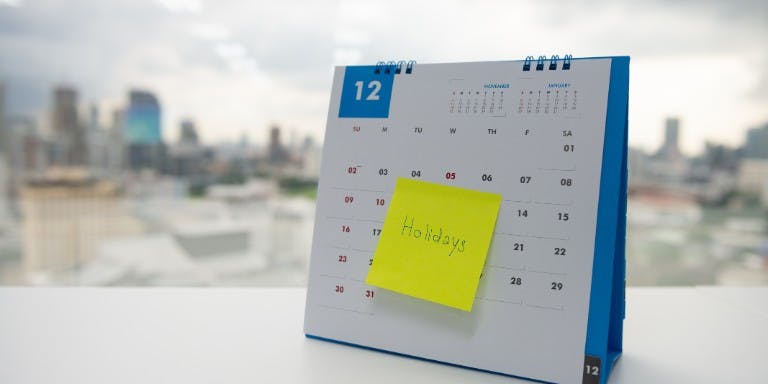 A calendar on a windowsill with a blurred city in the background