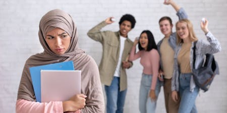 Types of discrimination Woman in a hijab holds a laptop, symbolising the challenges of workplace discrimination faced by diverse individuals.