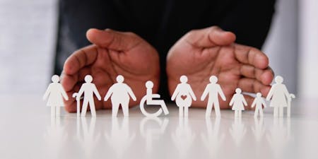 Indirect Discrimination person holds hands with paper cutouts of people, illustrating the theme of unity while highlighting the issue of indirect discrimination.