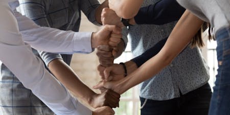 Employees of various backgrounds holding hands, representing collaboration and strong engagement within the team Engage employees