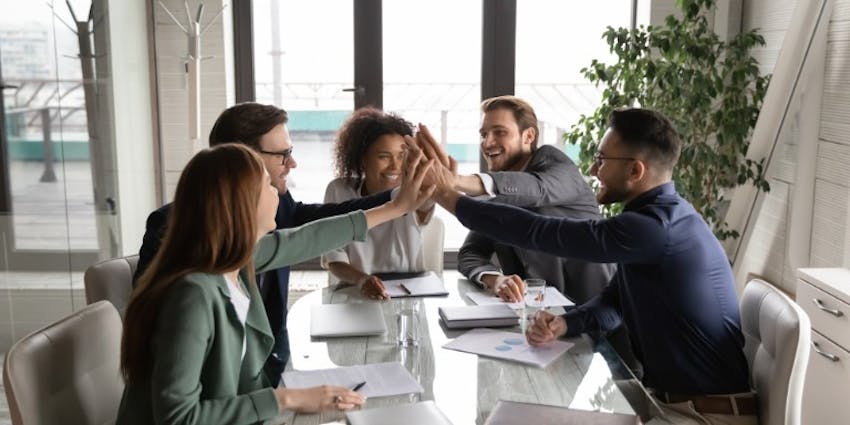 Group of business colleagues exchanging high fives, representing enthusiasm and strong employee engagement in their work