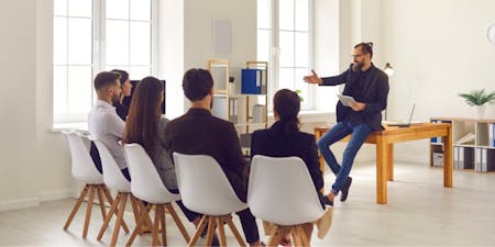 Employee training Male employer presents to a group during an employee training session, engaging the audience with informative content.
