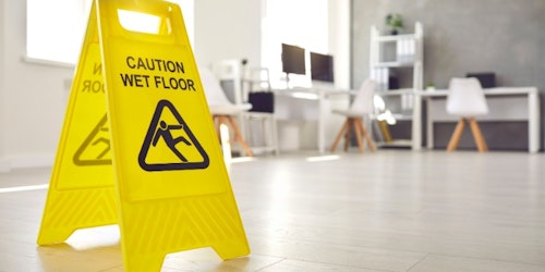 A wet floor sign placed on the office floor, indicating a potential hazard for employees and visitors.