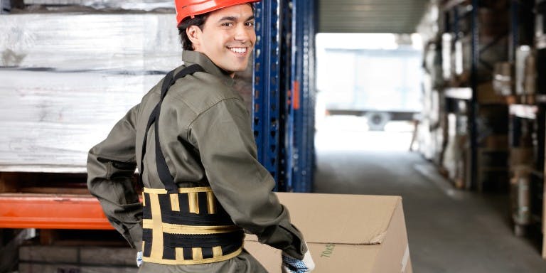 Man in a warehouse surrounded by boxes, demonstrating safe manual handling practices in the workplace.