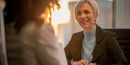 Woman in a business suit engages in a discussion with another woman, focusing on employee discipline matters.