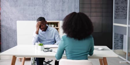 Disciplinary at work Man and woman are seated at a table in an office, discussing issues of discipline in the workplace environment.