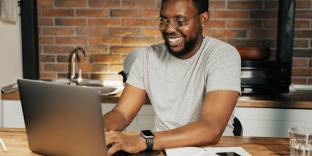 Payrolling Smiling man payrolling benefits in kind on a laptop at work.