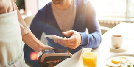 Fair tip distribution Man paying a tip with this apple pay in a cafe.
