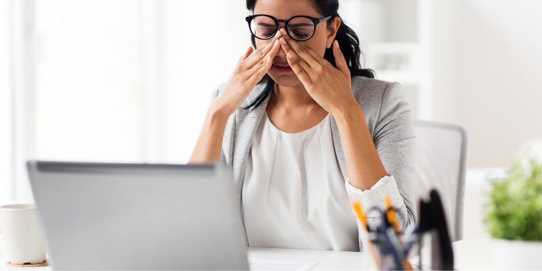 Eye protection at work DSE user rubbing her eyes, under their glasses due to eye strain from excessive use of laptop