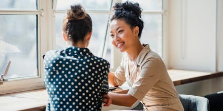 Disciplinary procedure Two women at a table in an office, participating in a discussion regarding a disciplinary procedure.