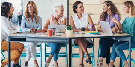 A diverse group of women engaged in a business meeting, discussing menopause support in the workplace.