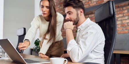 Employee onboarding Man and woman focus on a laptop, representing teamwork in the employee onboarding process.