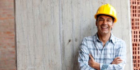 Temporary worker Temporary worker in a hard hat smiles confidently at the camera, showcasing a positive attitude on the job site.