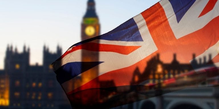 A union jack flying in front of the houses of parliament on an evening