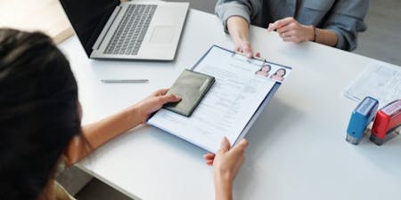 The Temporary Foreign Worker Program Employer at a desk holds a application for the temporary foreign worker program.