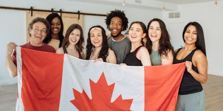 The Temporary Foreign Worker Program Diverse group of individuals proudly holding a Canadian flag, symbolizing unity and the Temporary Foreign Worker Program in Canada.