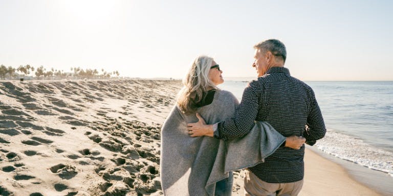 Superannuation Senior couple enjoying a leisurely walk on the beach, symbolising the joy of retirement and superannuation benefits.