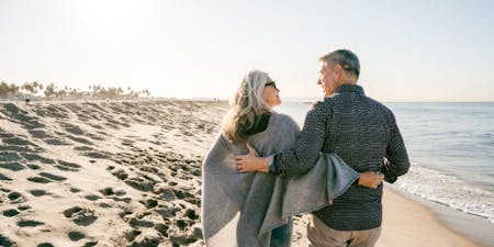 Superannuation Senior couple enjoying a leisurely walk on the beach, symbolising the joy of retirement and superannuation benefits.
