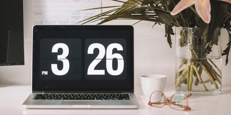 A desk with a laptop displaying the time and date.