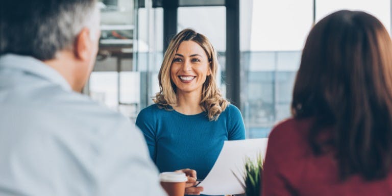 Female business owner speaks with her business partners at a meeting focused on Employer National Insurance matters.