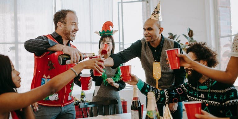 A group of colleagues celebrating the Christmas season together with drinks and festive accessories