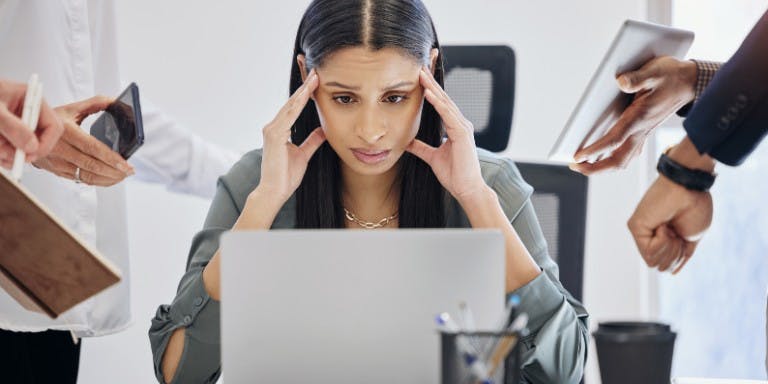 Employee overwhelmed with workload sat at desk