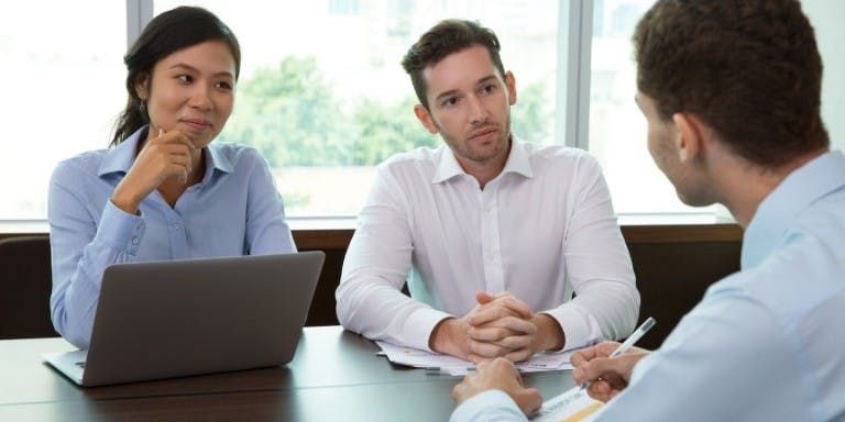 Performance review meeting Three colleagues in a meeting sitting around a desk