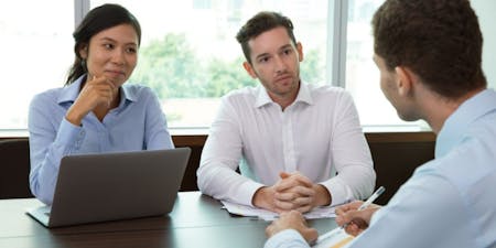 Performance review meeting Three colleagues in a meeting sitting around a desk