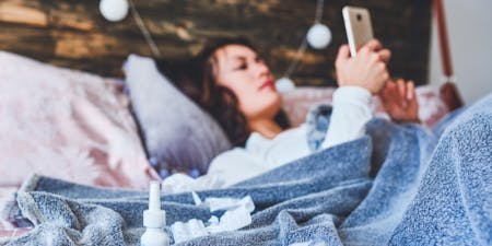 Employee notifying manager of sick leave from bed using their mobile device Record of employee sickness and absence