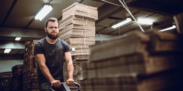 Male worker on night shift in a warehouse moving boxes