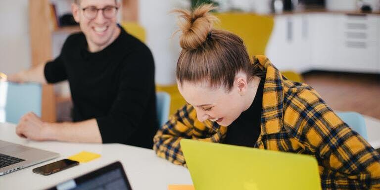 Employees laughing and happy at a desk.