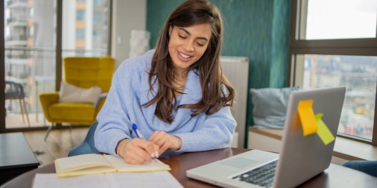 A woman sat studying with an e-learning course on a laptop