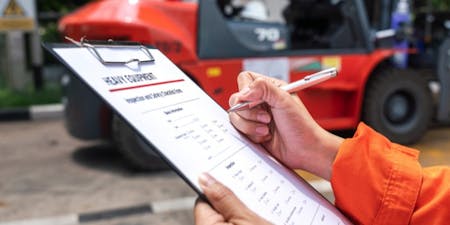 Work equipment health & safety An employer conducting a risk assessment of a piece of heavy machinery used within the workplace