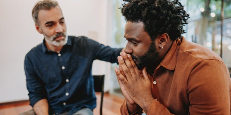 wo men engaged in a thoughtful conversation in a room, demonstrating emotional intelligence through their expressions and body language.