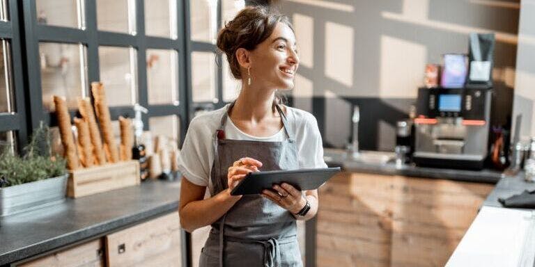 Employee clocking in to work at a cafe using an clock in system on a tablet.