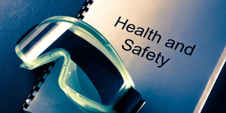 A pair of safety goggles sat on a health & safety manual