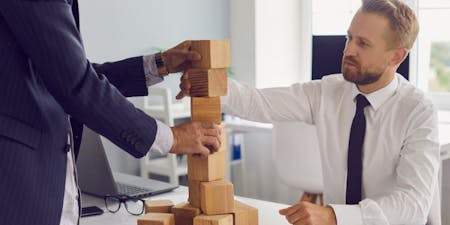 Career progression meeting to discuss the steps required for growth Employee and manager building a tower of blocks in a meeting
