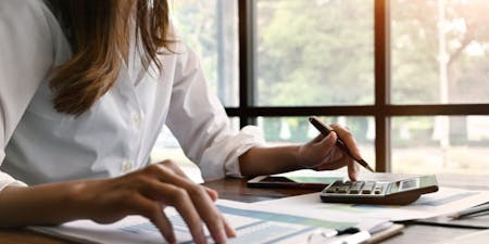 Calculating holiday accrual Woman using a calculator and paperwork to calculate employee annual leave accrual