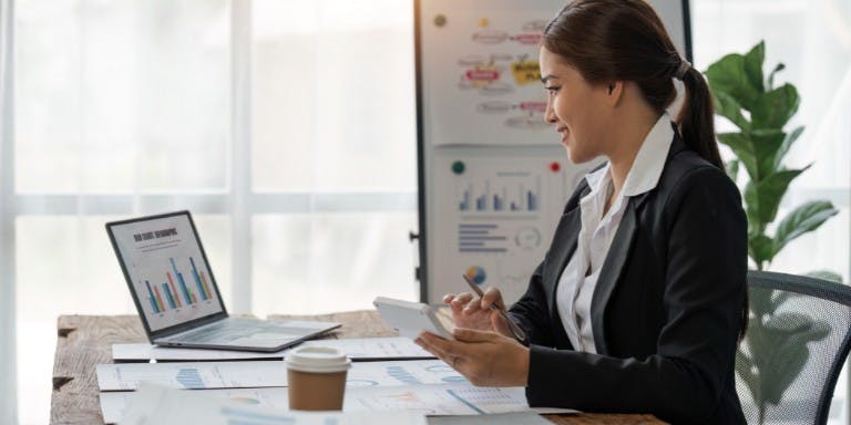 Businesswoman at her desk with a laptop, preparing for the upcoming Spring Forecas