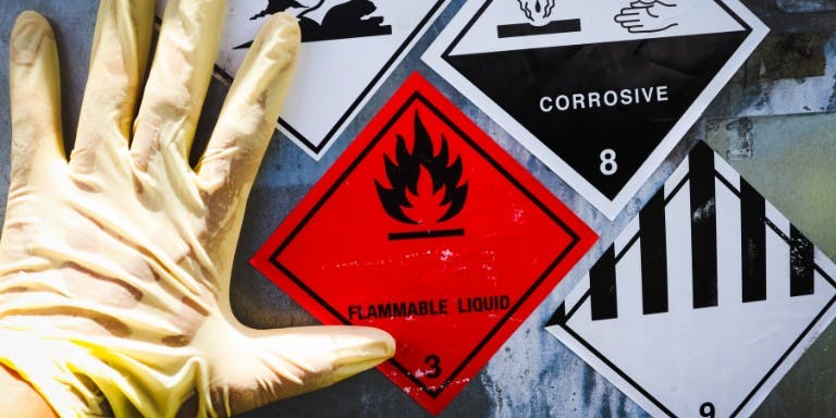 COSHH A gloved hand next to hazardous substance symbols in line with COSHH regulations.