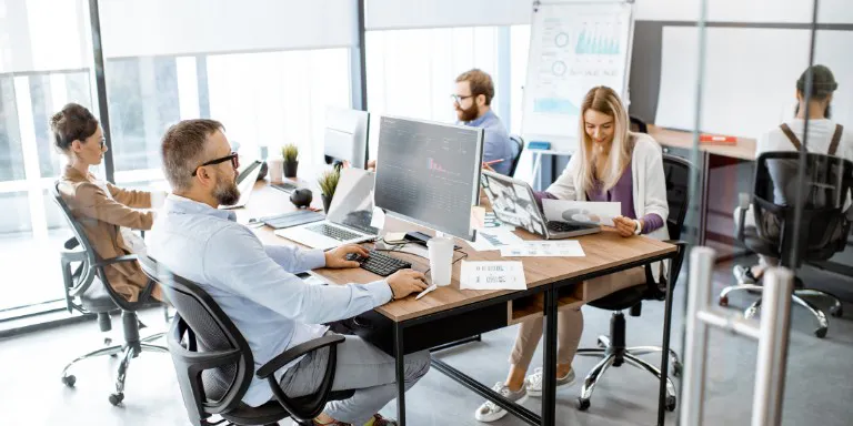 Group of employees working on computers in an office setting.