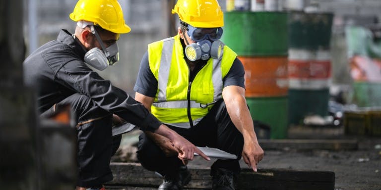 Two men in safety gear conduct COSHH assessments.