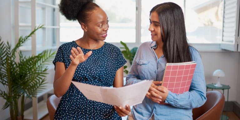 Female employer mentoring a female employee in an office setting.