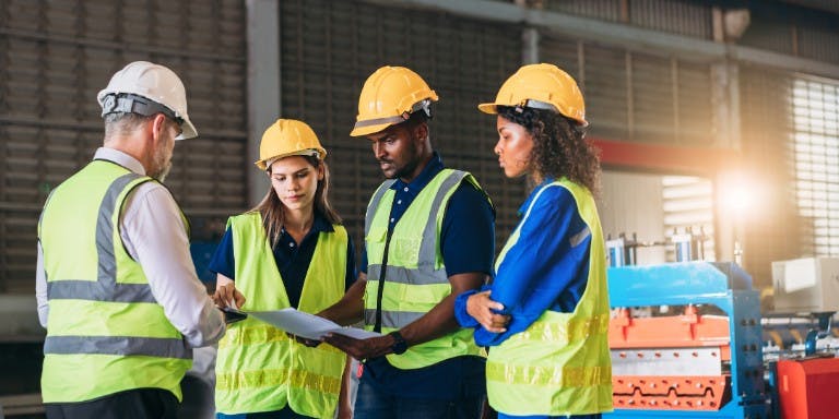Workers in a manufacturing factory checking safety data sheets for a COSHH assessment