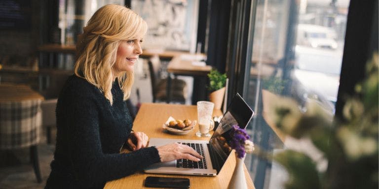 A worker working remotely in a cafe from her laptop under flexible working conditions