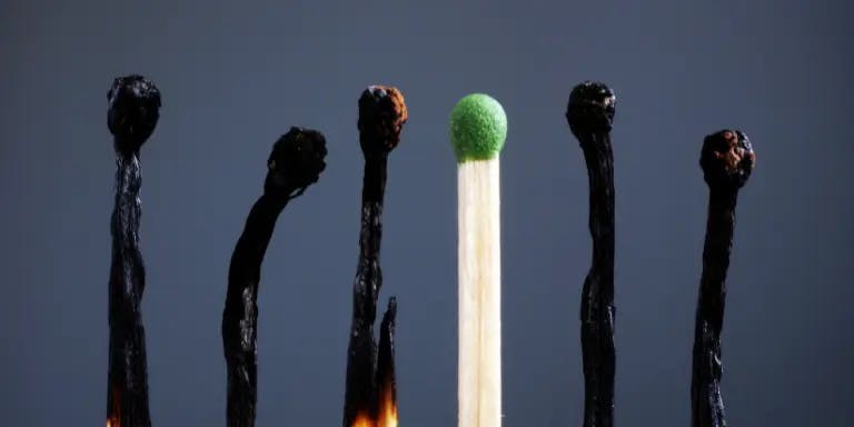 Matchsticks in a row, with all but one burned out, symbolising burnout at work
