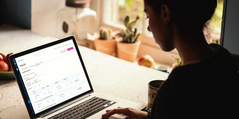 A woman completing a payroll run using BrightHR payroll software on her laptop