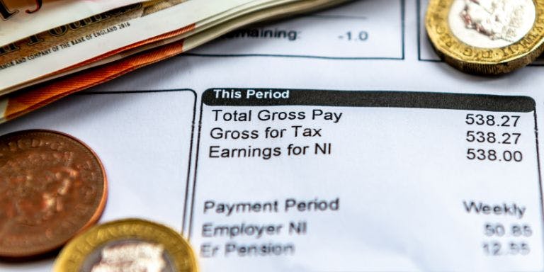 A paper payslip displaying total gross and more payroll information