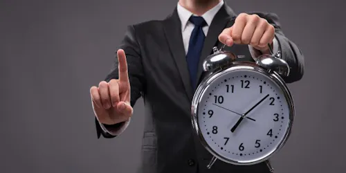 A manager holding a clock and monitoring employee time