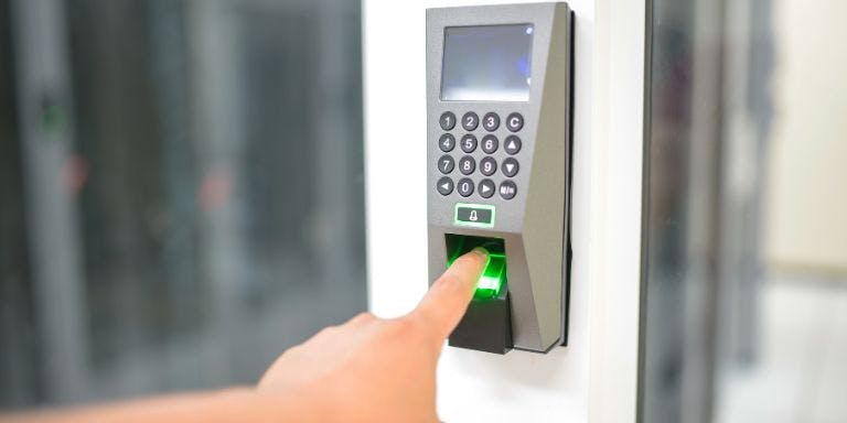 Biometric fingerprint scanning clock in system for employees An employee using their fingerprint to scan their entry into work with a biometric clock in system